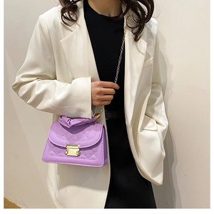 Detalle de bolso acolchado morado con cierre dorado y correa de cadena en una modelo