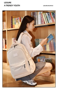 Cream colored college backpack shown against bookshelves in a library setting