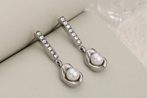 Macro detail of silver pearl drop earring with sparkling zircon inlay and wavy metal base