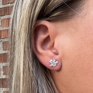 Close-up of geometric silver stud earring with clear rectangular zircons on ear