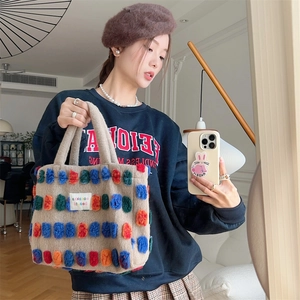 Model posing with beige plush bucket bag decorated with vibrant colorful fur pom-poms
