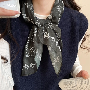 Detail of dark green printed silk scarf tied around neck with ethnic floral patterns