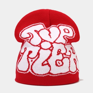 Detail of red knit beanie featuring white graffiti heart lettering and ribbed cuff finish