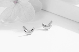 Macro shot of silver crescent moon stud earrings on a clean white background