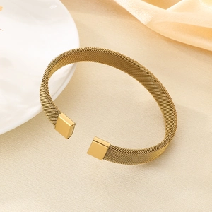 Vista macro dettagliata della trama a maglia intrecciata dorata su un bracciale rigido aperto