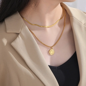 Close-up of double-layer gold necklace featuring a crown relief pendant on the model