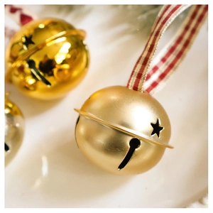 Macro view of champagne gold star cutout bells with red plaid ribbon for Christmas tree