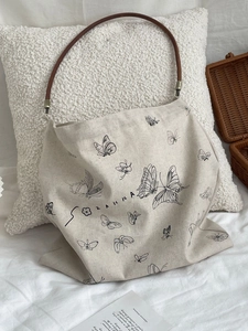 Canvas butterfly print tote bag with dark brown top handle on minimalist background