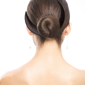 Detail of a crescent moon hair fork in black wood securing a bun hairstyle