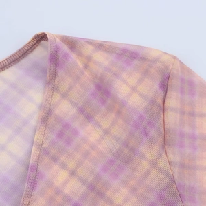 Détail du tissu en maille transparente montrant l'imprimé à carreaux violet et orange sur l'épaule