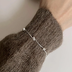 Minimalist S925 sterling silver beaded bracelet on a brown mohair sweater sleeve