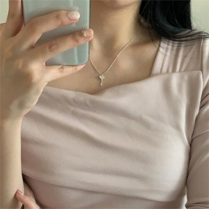 Detail of silver heart key pendant on a fine chain worn for a minimalist neck look