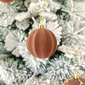 Gros plan d'une boule de Noël en velours marron avec texture verticale et cordon doré