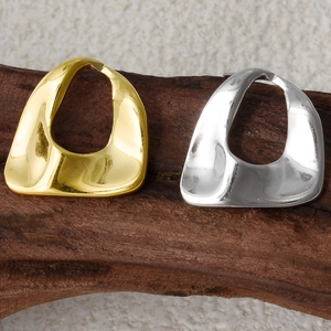 Macro shot of 304 stainless steel oval geometric earrings on rustic wood in gold and silver