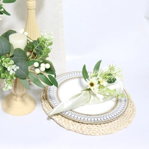 Close-up of artificial willow leaf napkin ring with silk flower on golden rimmed ceramic plate
