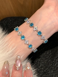 Close-up of silver flower bracelets with blue zircon stones on a model's wrist