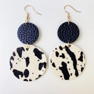 Détail de boucles d'oreilles en cuir bleu marine et fausse fourrure à motif vache