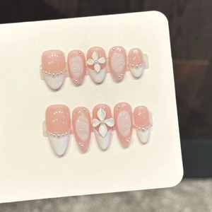 Macro detail of handmade pink press-on nails with 3D floral carving and pearl accents