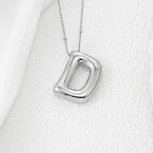 Macro shot of a silver D-shaped balloon pendant necklace with realistic fold details