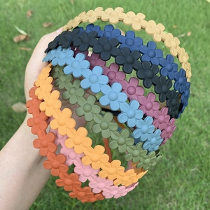 Matte floral headbands in various candy colors held over a green lawn background