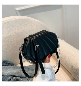 Detailaufnahme der schwarzen Muscheltasche mit Perlengriff und gesteppter Ledertextur