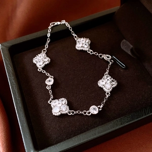 Detailed view of silver clover bracelet with white zircons on brown silk backdrop