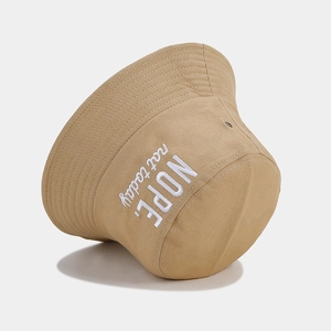 Detail of khaki cotton bucket hat featuring white NOPE embroidery and metal eyelets