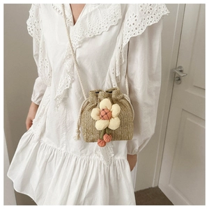 Dettaglio mini borsa a secchiello in paglia con fiore in tessuto 3D e pompon ciliegia
