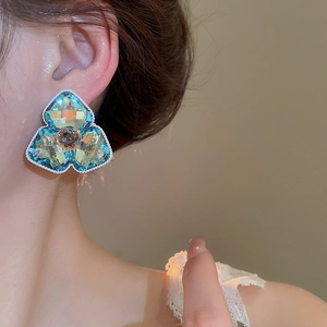 Nahaufnahme großer blau-gelber Kristall-Ohrringe in Blumenform an einem Modell mit Silber