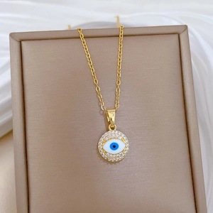 Macro detail of gold evil eye necklace with crystals and enamel on jewelry box