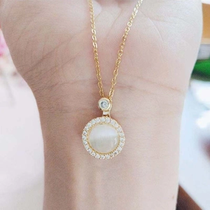 Close-up of golden spinning necklace with white cat eye stone and tiny cubic zirconia