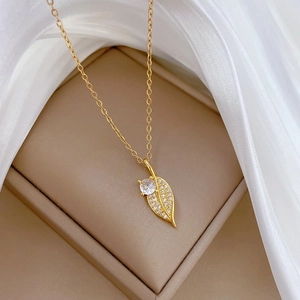 Elegant gold leaf pendant necklace with crystals on white silk in a jewelry box
