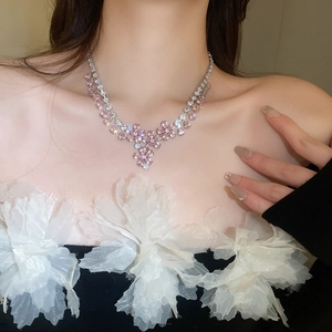 Dettaglio della collana con ciondolo a fiore rosa e zirconi indossata dal modello