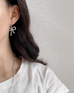 Detail shot of 925 sterling silver bow earrings with zircon stones worn by a model