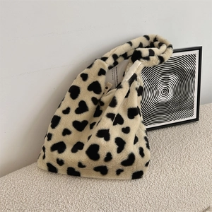 Detail of soft apricot plush tote bag featuring black heart prints and wide handle