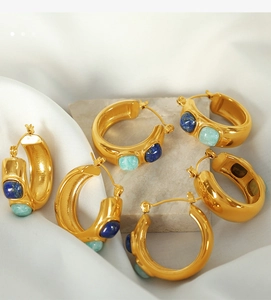 Detail of C-shaped gold-plated hoop earrings featuring inlaid blue natural stones on silk