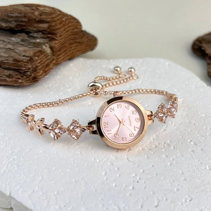 Detail of rose gold quartz watch with pink dial and rhinestone strap on white stone