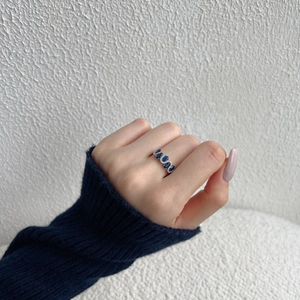 Detail of S925 silver wave ring with blue oval gemstone and white diamonds on hand