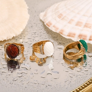 Detailed shot of 18K gold plated ring with emerald acrylic stone on mirror surface