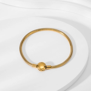Detail view of 18K gold snake chain bracelet with round clasp on a textured stand