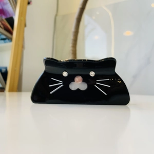 Detail of a black cat acetate hair claw clip featuring rhinestone eyes and white whiskers