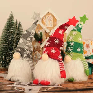 Close-up of three lighted Christmas gnomes with snowflake knitted hats and stars