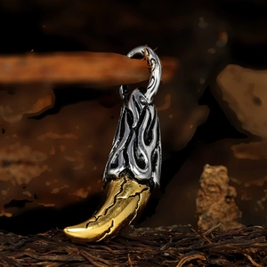 Detailed macro view of two-tone gold and silver wolf tooth pendant on a dark wooden background