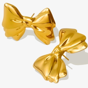 Detail of 18k gold plated stainless steel bow earrings with a polished metallic finish