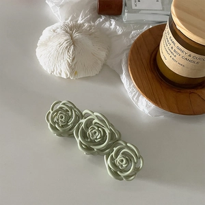Detail of matte green triple rose hair claw clip styled with Nordic home decor accents