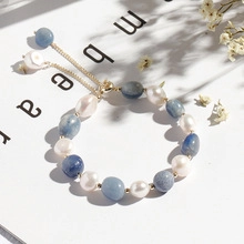 Detail of beaded bracelet with white pearls, blue stones and adjustable gold chain