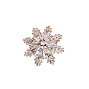 Elegant gold snowflake brooch with sparkling white cubic zirconia stones on white background