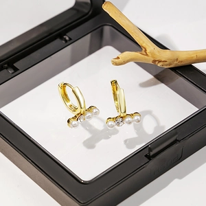 Détail de la boucle d'oreille cœur dorée avec perles d'imitation et zircon facetté