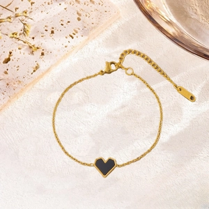 Vue détaillée du collier doré avec pendentif cœur et étiquette K15 sur un support en pierre