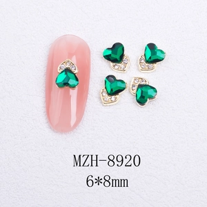 Detail of 6x8mm heart-shaped green cat eye nail charm with gold base and rhinestones